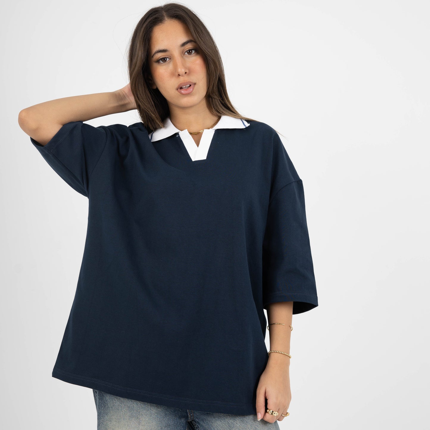 Woman wearing a navy blue oversized shirt with a white collar on a white background