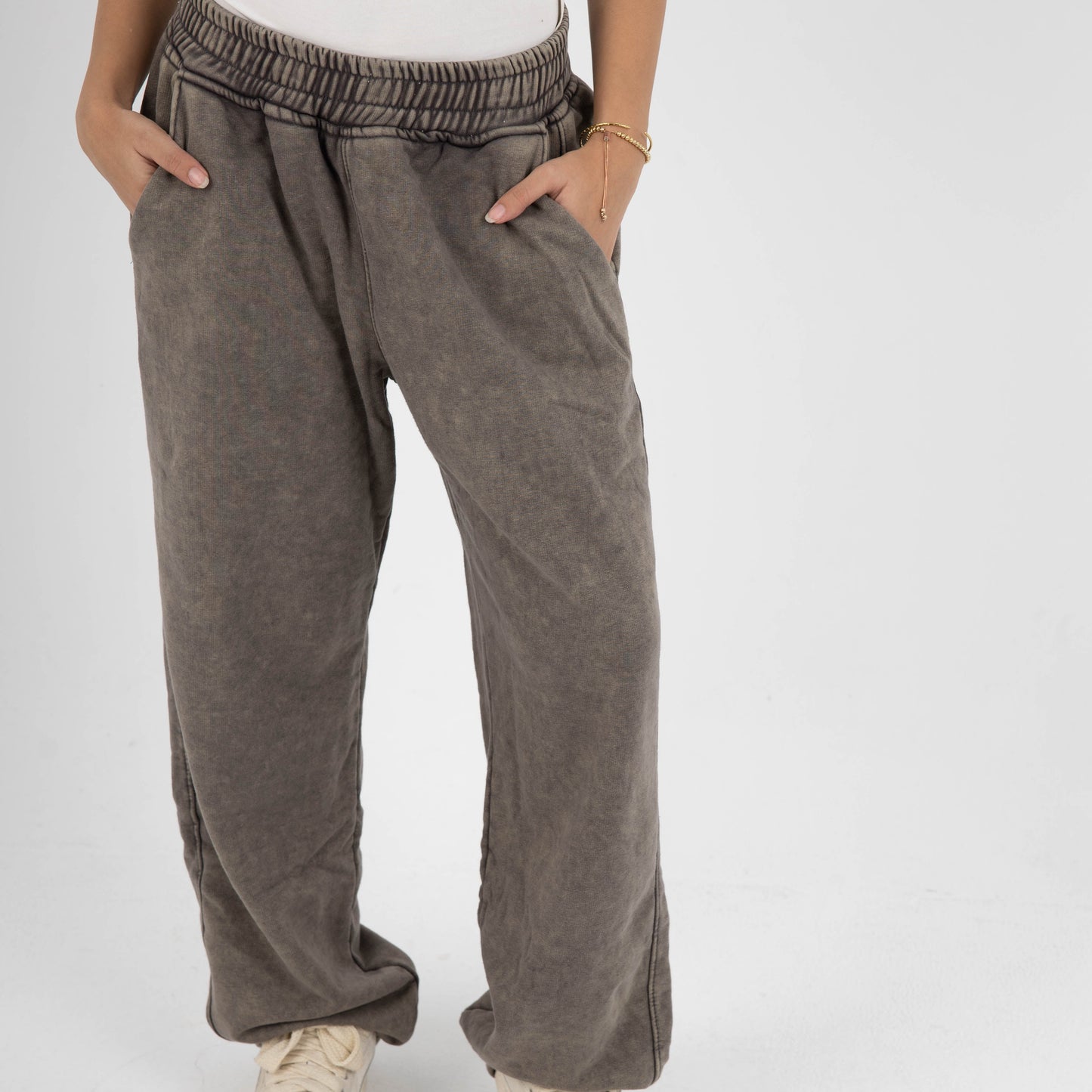 Person wearing brown wide-leg pants and white sneakers on a white background