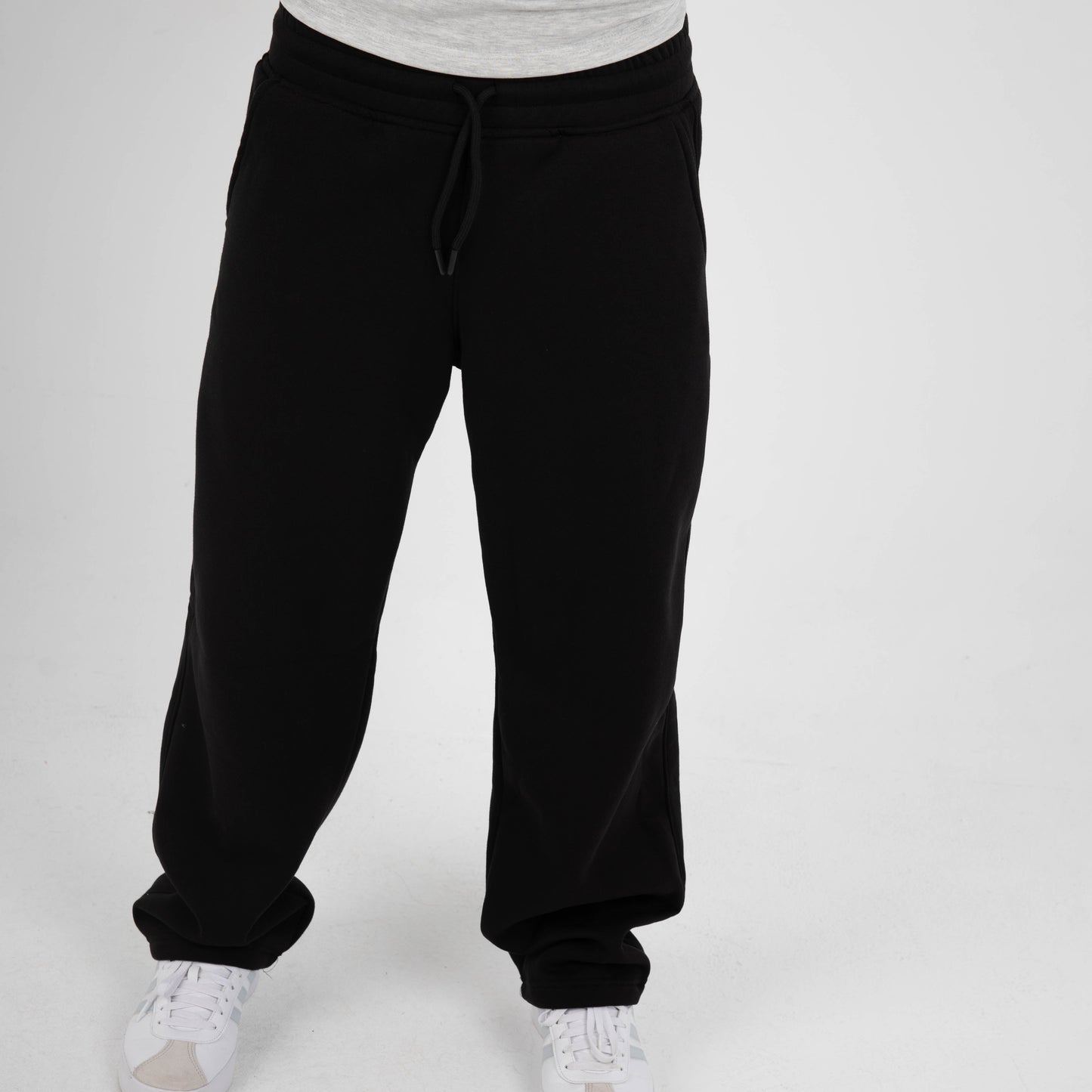 Person wearing black sweatpants and a gray shirt on a white background