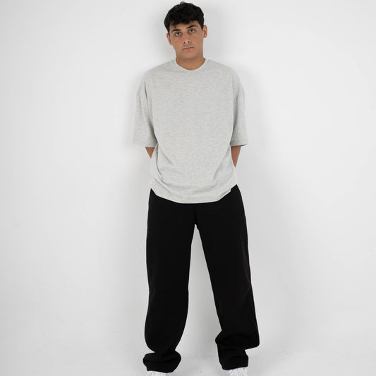 Person wearing a gray sweater, black pants, and white shoes on a white background