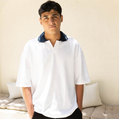 Man wearing a white shirt with a blue collar in an outdoor setting