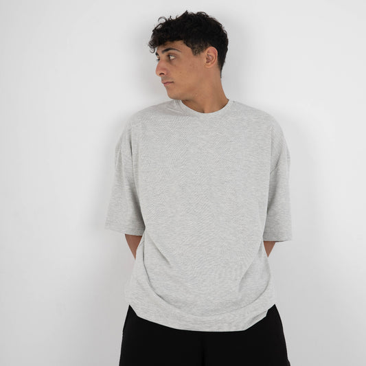 Person wearing a gray sweater and black pants against a white background